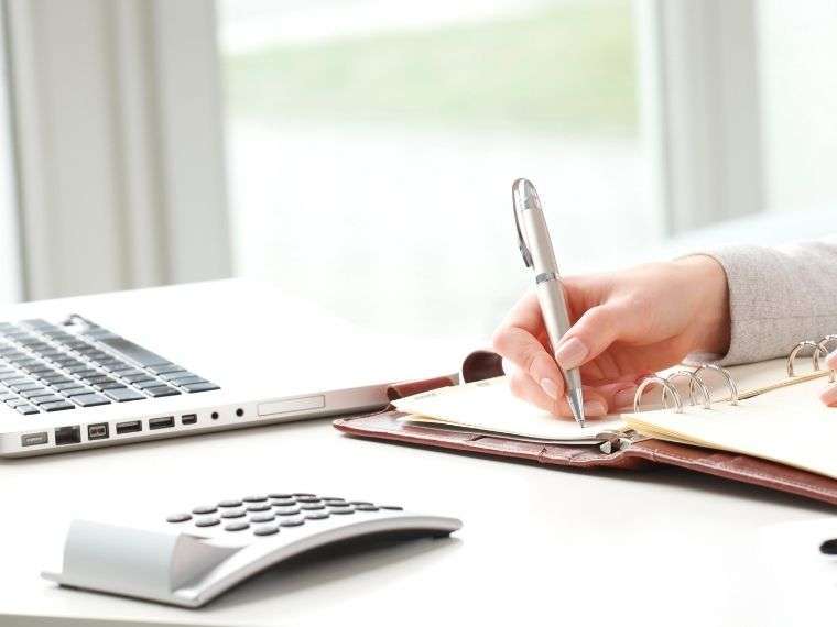 woman at computer with pen and paper