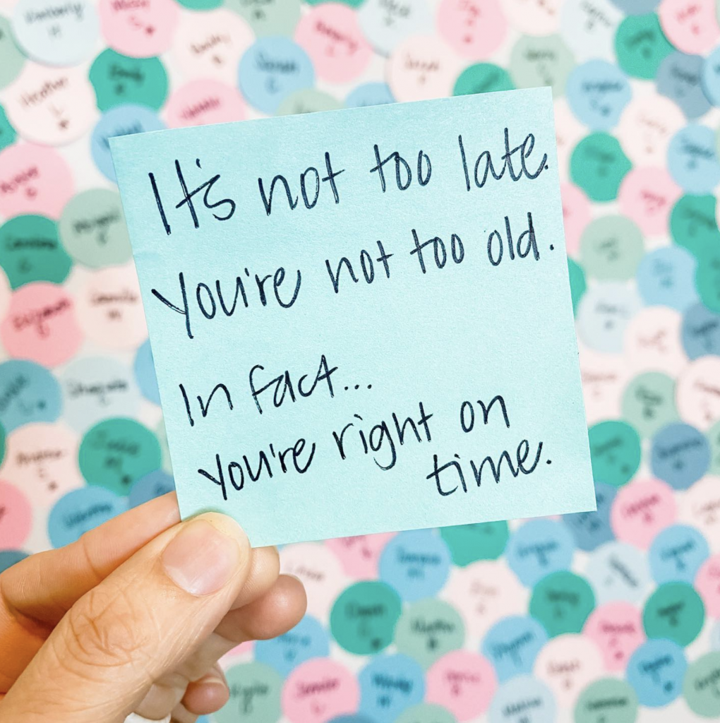 A hand holding a post it note with writing