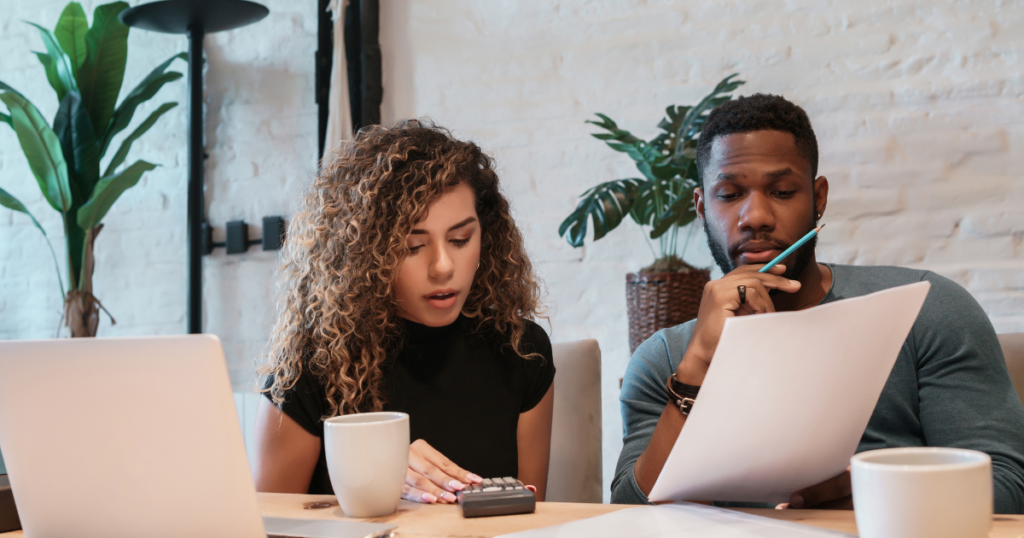 A couple looking at a financial plan, with one partner pointing to a chart while the other holds a laptop open to a budgeting page